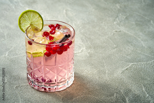 Alcoholic pink cocktail with cranberry and ice in a glass. Concrete background. Vermouth with vodka