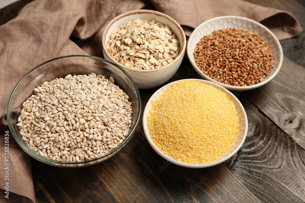 Bowls of different cereals on wooden table, closeup Bowls of different cereals on wooden table, closeup