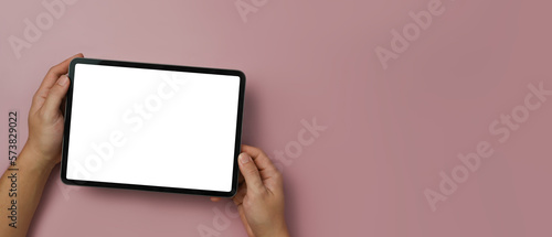 Above view of man hands holding digital tablet with empty display over pink background. Copy space for your text