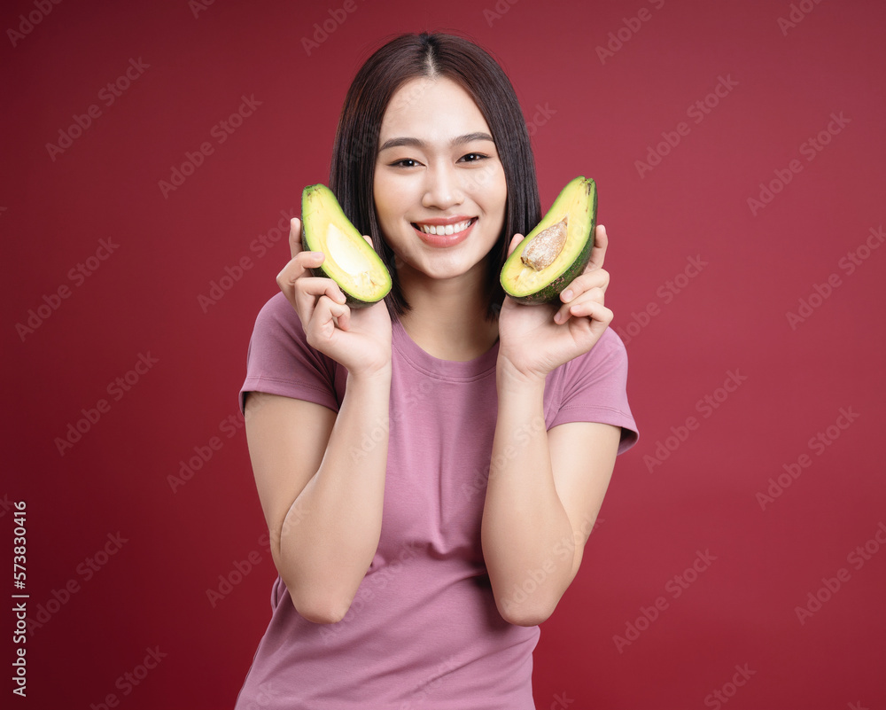 Young Asian woman holding avocado fruit on background Young Asian woman holding avocado fruit on background