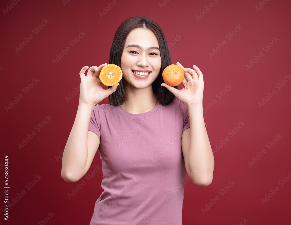 Young Asian woman holding orange fruit on background Young Asian woman holding orange fruit on background