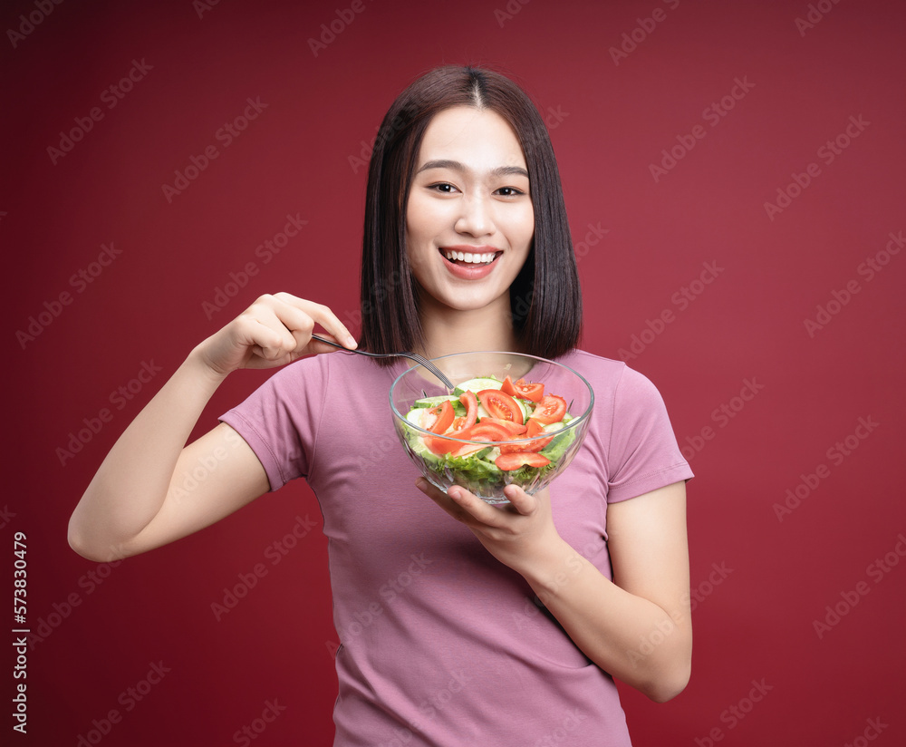 Young Asian woman eating salad on background