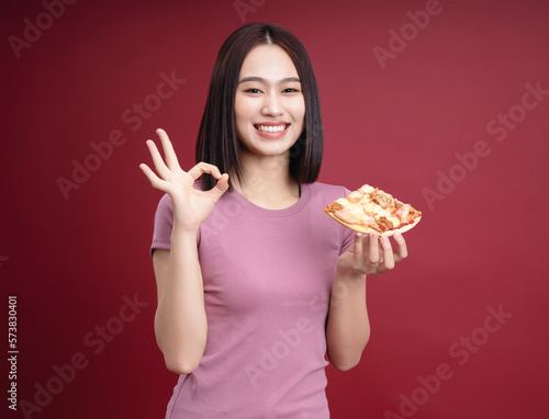 Young Asian woman eating pizza on background