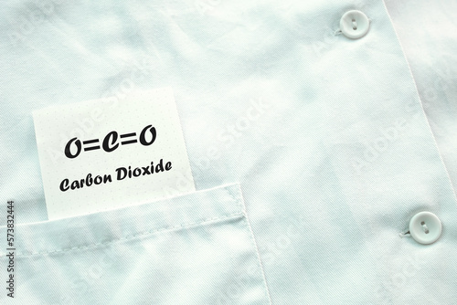 CO2 carbon dioxide formula written on a note placed in the pocket of a laboratory coat.