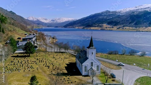 Old white color wooden church and cemetery near lake, aerial view