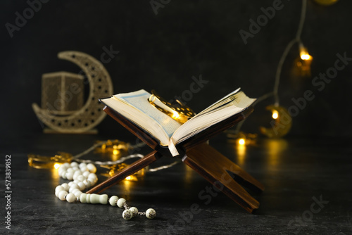 Rehal with Koran, tasbih and glowing lights for Ramadan on dark background photo