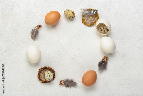 Frame made of Easter eggs and feathers on white background