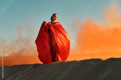 Woman in red dress dancing in the desert