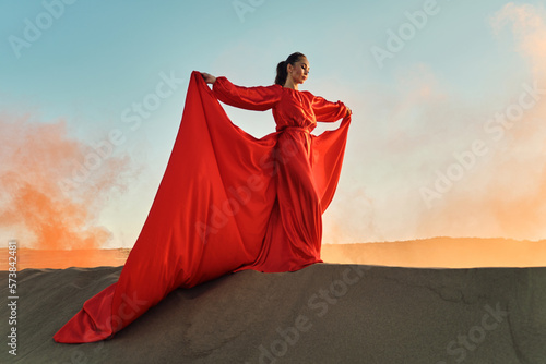 Woman in red dress dancing in the desert