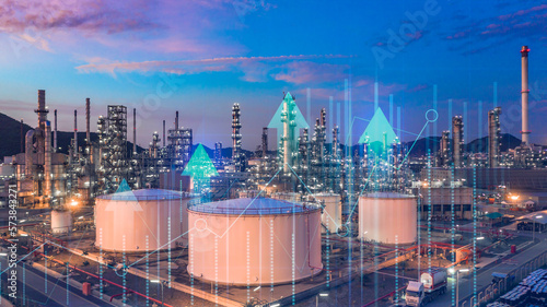 Foto Oil​ refinery​ with oil storage tank with price graph and petrochemical​ plant industrial background at twilight, Aerial view oil and gas refinery at twilight