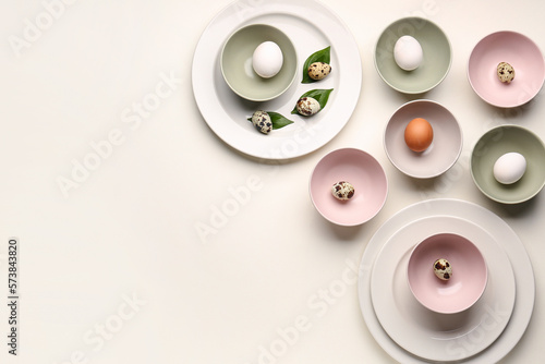 Composition with set of plates, bowls and Easter eggs on white background