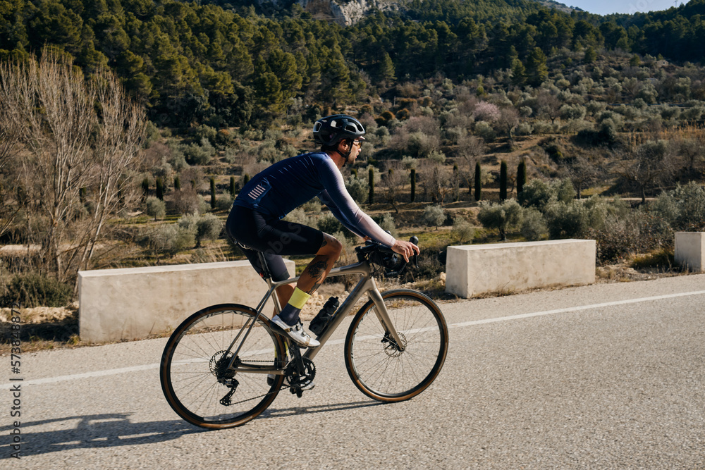 Obraz premium A professional sports cyclist riding fast uphill.A man riding a gravel bike.Sport motivation. Alicante, Spain