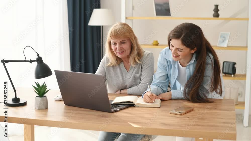 Sitting and using laptop. Mother and daughter is together indoors. Sitting and using laptop. Mother and daughter is together indoors.