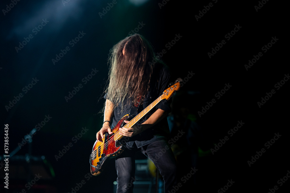 Guitarist on stage playing bass guitar at a rock concert