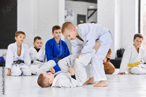 Little boys, children in white kimono training judo, jiu-jitsu indoors. Professional sports club for kids. Concept of martial arts, combat sport, sport education, childhood, hobby photo