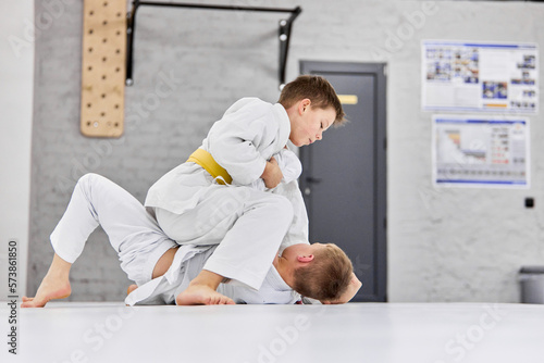 Future sportsmen. Boys, children in white kimono training, practising judo, jiu-jitsu exercises indoors. Concept of martial arts, combat sport, sport education, childhood, hobby