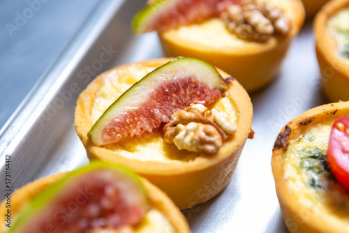 Delicious canape with fresh figs, walnut and melted cheese. Groupd of gourmet snacks for wine party being prepared in restautant kitchen