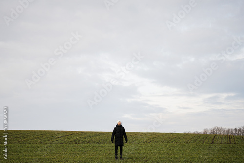 Teen boy wearing black jacket and white hat outside, enjoys in the early spring field.. © AS Photo Family