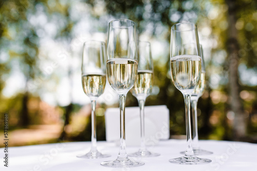 Bartender pouring champagne or wine into wine glasses on the table at the outdoors solemn wedding ceremony. High quality photo