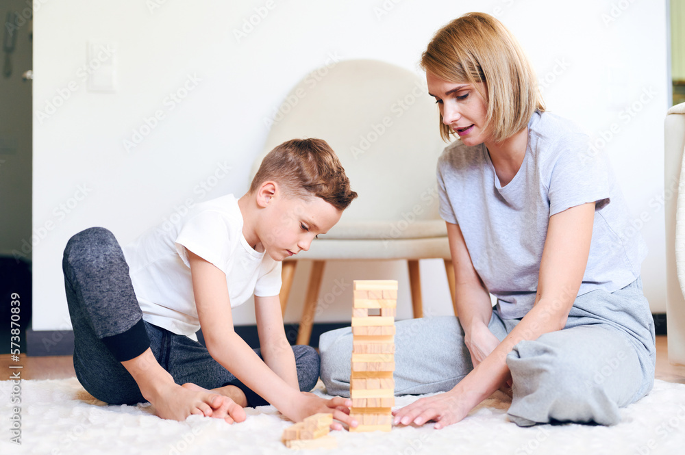 Cute little caucasian boy and his mother play board game on the floor at home Cute little caucasian boy and his mother play board game on the floor at home