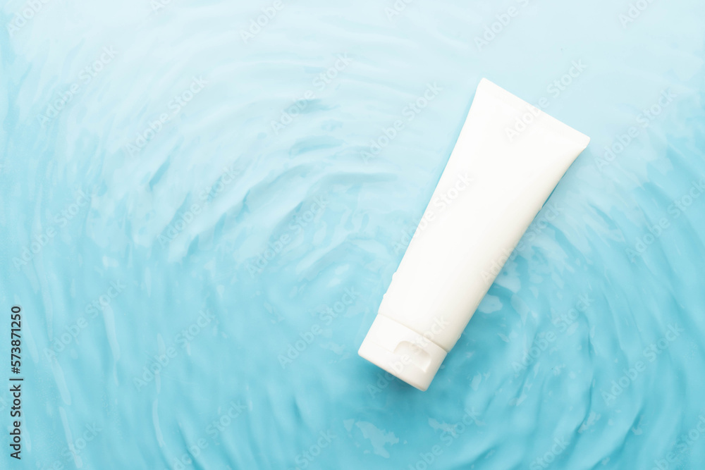 Blank white squeeze bottle plastic tube on blue water surface wtih waves. Packaging of moisturizing cream, cleansing gel or hydrating body lotion. Spa and skincare product branding mock up. Blank white squeeze bottle plastic tube on blue water surface wtih waves. Packaging of moisturizing cream, cleansing gel or hydrating body lotion. Spa and skincare product branding mock up.
