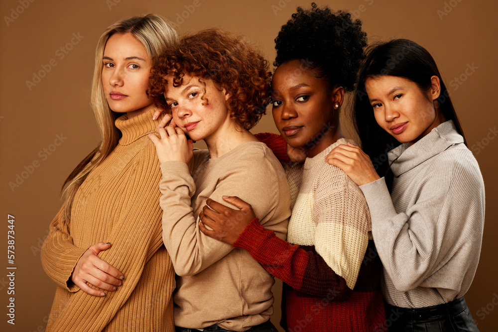 Fototapeta premium Studio shot of multicultural friends posing isolated on brown background and looking at the camera.