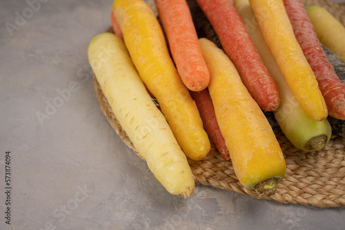 Colorful Rainbow carrot on gray background. Gradient of color carrots from yellow to purple, Yellow, orange and purple carrot.