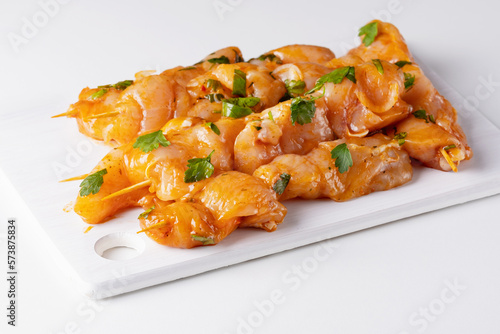 Schilderij op canvas Raw chicken skewers in marinade with spices on a white board