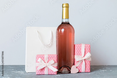 Bottle of wine on colored background for Valentine Day with gift box. Heart shaped with presrnt box perspective view with copy space photo