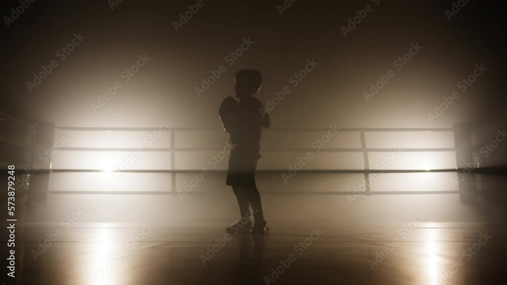 Physical training of young, active boy in boxing ring improving his punches and hitting. Close-up view of a child's silhouette working out alone. High quality 4k footage Physical training of young, active boy in boxing ring improving his punches and hitting. Close-up view of a child's silhouette working out alone. High quality 4k footage
