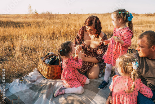 Foto Young family with triplet girls on picnic, eco-friendly paper tubes, biodegradable materials