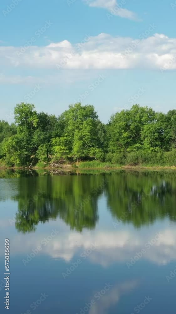 Flying over the calm summer lake in forest, sky reflection. Vertical video Flying over the calm summer lake in forest, sky reflection. Vertical video