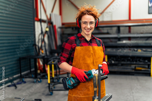 Canvastavla A young girl with curly red hair who is an apprentice in a metal workshop is usi