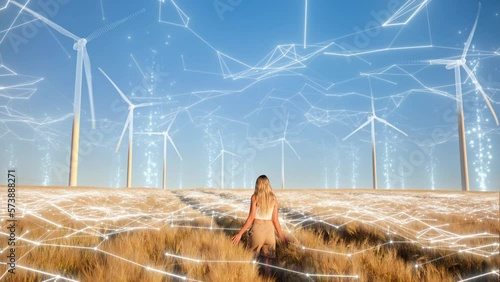 Clean energy, environment and sustainability concept. Young blond girl walks through a golden wheat field with wind turbines on the horizon and dreams of a clean and sustainable future for humanity