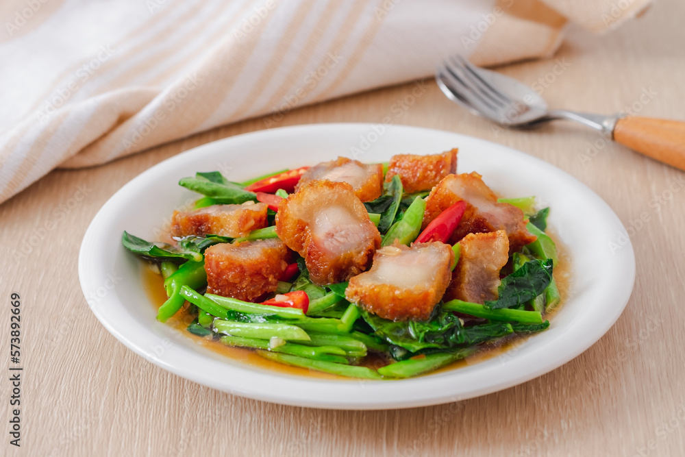 Stir fried kale with crispy pork in oyster sauce on white plate Stir fried kale with crispy pork in oyster sauce on white plate