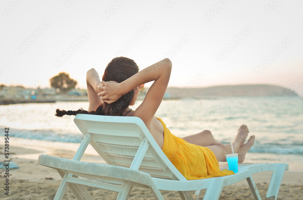 young woman lying on deck chair back to back in the sea
