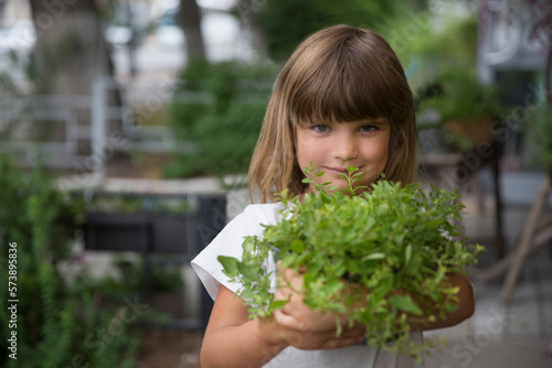 child girl holding pot with mixed green fresh aromatic herbs in garden near the house. enjoy the little things. favorite family hobby. Eco-friendly. 