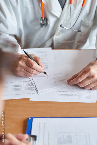 vertical shot of male doctor writing medical prescription to patient © Carlos