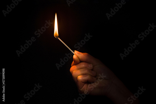 A burning match in hand. Hand with a burning match in the dark.  photo