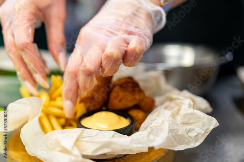 woman chef cooking Chicken Nuggets with French Fries and sauce on kitchen
