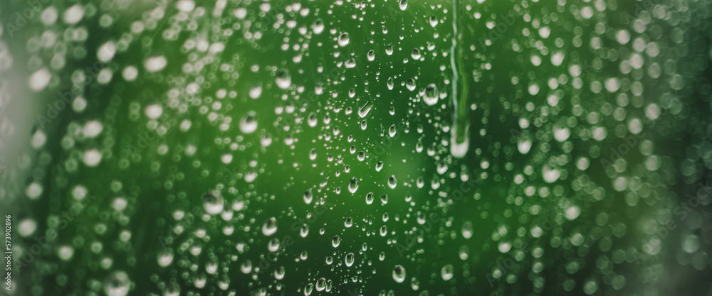 Atmospheric minimal backdrop with rain droplets on glass. Wet window with rainy drops and dirt spots closeup. Blurry minimalist background with greenery bokeh against dirty window glass with raindrops Atmospheric minimal backdrop with rain droplets on glass. Wet window with rainy drops and dirt spots closeup. Blurry minimalist background with greenery bokeh against dirty window glass with raindrops