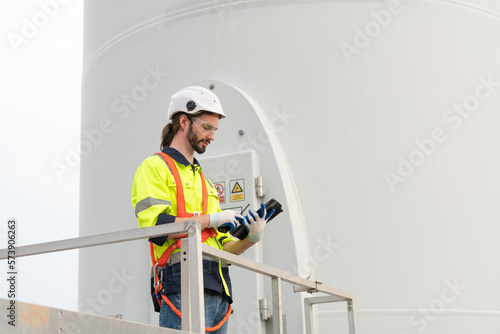 Male engineer windmill wearing uniform and helmet using tablet inspection and check wind turbine in wind farms to generate electrical energy, Renewable energy.