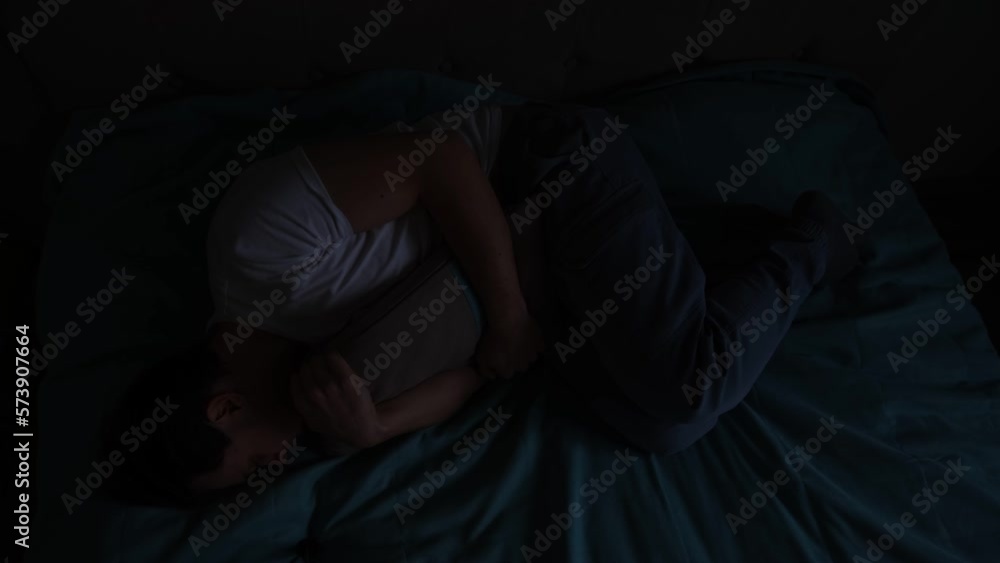 Depressed suicidal man in darkness anxiety hugging pillow on couch pulsing light his breast. Sad desperate person with chronic disease difficulties ask for help with his hand reaching camera Depressed suicidal man in darkness anxiety hugging pillow on couch pulsing light his breast. Sad desperate person with chronic disease difficulties ask for help with his hand reaching camera