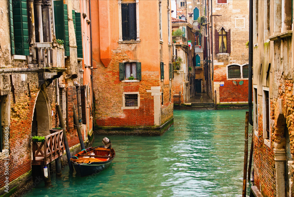 Typical cityscape view of Venice. Narrow canal with emerald water between ancient red brick buildings. Famous touristic place and travel destination in Europe. Winter drizzle day in Venice