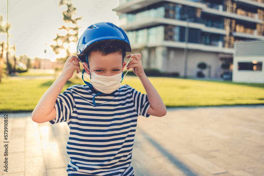 Caucasian boy posing with a protective mask, bicycle helmet. A little boy sits on a bicycle and puts on a protective mask before his ride. Caucasian boy posing with a protective mask, bicycle helmet. A little boy sits on a bicycle and puts on a protective mask before his ride.