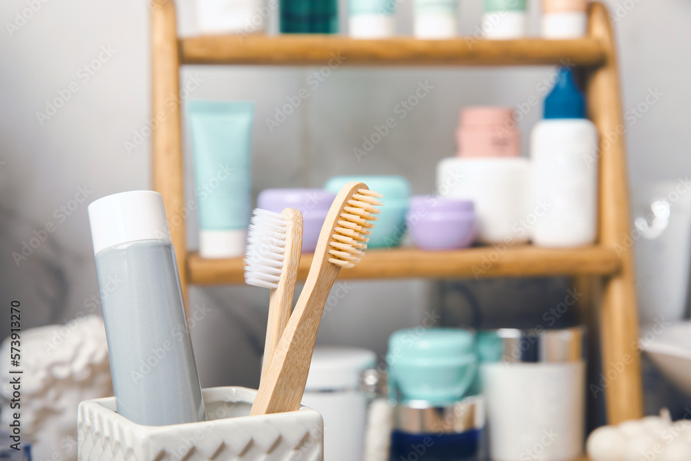 Eco bamboo toothbrushes and toothpaste tube mockup in the bathroom. Toothbrushes on the background of cosmetics on the shelf. Beauty concept. Dental car.