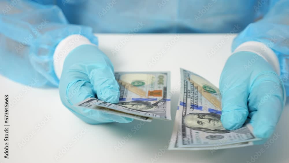 Professional worker counts money and checks dollar banknotes for fakeness in bank. Employee holds visual review and verification of money for authenticity Professional worker counts money and checks dollar banknotes for fakeness in bank. Employee holds visual review and verification of money for authenticity
