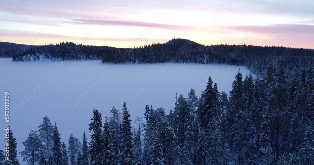An aerial of a coniferous Northern forest and a hill in the horizon during wintry sunrise near Kuusamo, Northern Finland An aerial of a coniferous Northern forest and a hill in the horizon during wintry sunrise near Kuusamo, Northern Finland