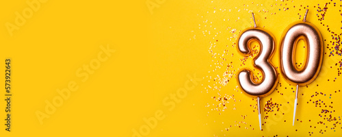 30 years celebration. Greeting banner. Gold candles in the form of number thirty on yellow background with confetti.