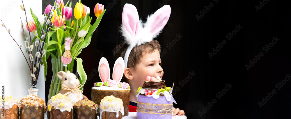 Cute little boy with bunny ears looking at tasty easter sweet cake